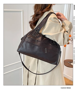 Detail view of retro brown shoulder bag with double parallel zippers and leather texture