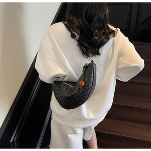 Detail of black woven crescent bag with wide knotted strap and amber bead zipper