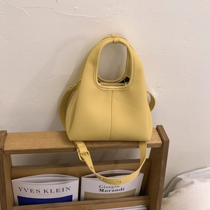 Macro detail of ginger yellow pebbled leather bucket bag with vertical stitching and strap