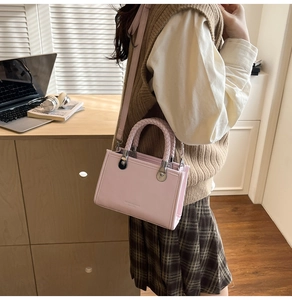 Detail view of pink square bag with woven handle, fashion lettering and silver hardware