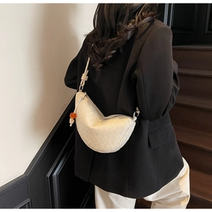Detail of woven crescent bag with knot strap and orange bead accent on female model