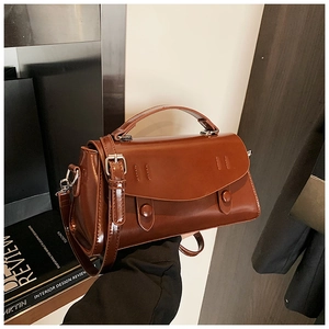 Close-up of gloss leather handbag texture with dual round buckle details and top handle