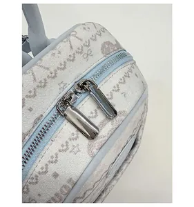 Detail of double silver metal zippers on light blue backpack with bow prints