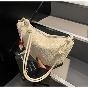 Detail of cream woven saddle bag featuring unique rope knot strap and orange bead detail