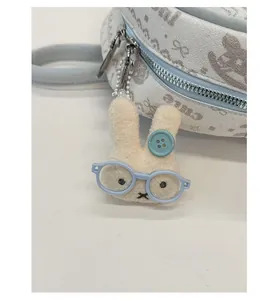 Close-up of light blue fabric bag featuring a cute plush bunny charm with glasses