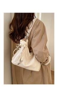 Close-up of cream soft PU leather tote bag featuring side zipper and plush mascot charm