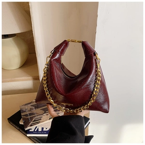 Détails de la texture du cuir verni bordeaux et des maillons de la chaîne dorée