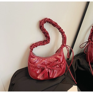 Detail of dark red pleated leather shoulder bag with scrunchie strap and bow decoration