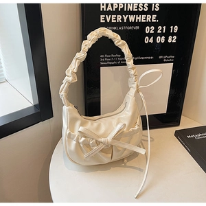Close-up of stylish off-white pleated shoulder bag with scrunchie handle and ribbon detail