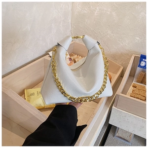 Détail du sac à main en cuir verni blanc avec grosse chaîne dorée et fermoir supérieur