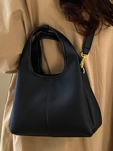 Minimalist black lychee texture bucket bag with gold hardware and shoulder strap