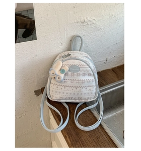 Close-up of a blue and beige mini backpack with Nordic snowflake patterns and rabbit charm