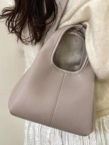 Minimalist lavender lychee leather bucket bag with wide handle shown in a lifestyle setting