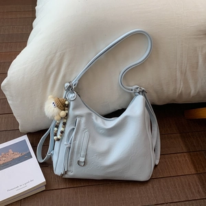 Detail of light blue faux leather hobo bag featuring silver hardware and a plush charm
