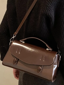 Minimalist dark brown glossy crossbody bag with dual buttons and adjustable strap