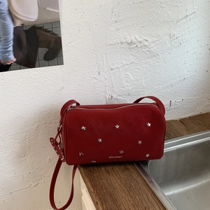 Macro detail of dark red handbag featuring silver star studs and smooth leather texture