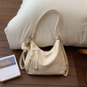 Detail of a creamy beige hobo bag with lychee texture and a cute white sheep charm