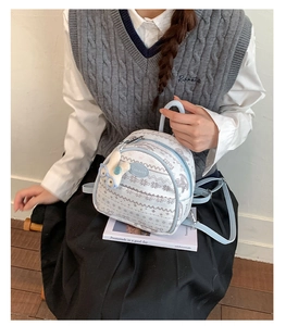 Close-up of a blue floral mini backpack with a cute rabbit plush charm on a book