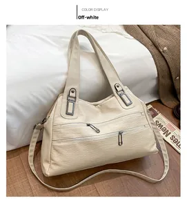 Cream white faux leather tote bag with dual zippers and long strap in home setting