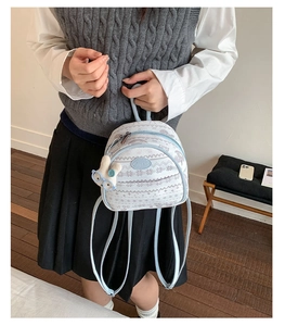 Detail of light blue mini backpack featuring snowflake pattern and plush bunny pendant accessory