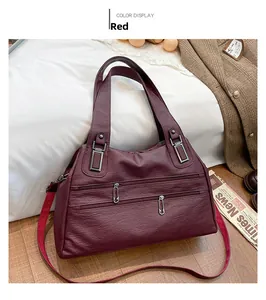 Close-up of wine red faux leather handbag featuring litchi grain texture and zippers