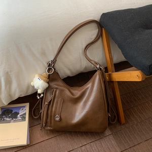Close-up of brown vintage PU leather hobo bag with front zip and plush sheep keychain