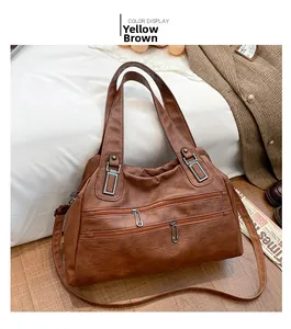 Detail view of yellow-brown multi-pocket shoulder bag with silver metal zippers on white bedding