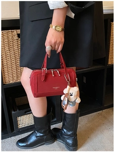 Dettaglio borsa Boston rossa con charm a forma di orso tenuta da una modella