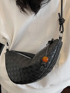 Black woven leather crescent bag with amber bead charm shown on a casual white T-shirt