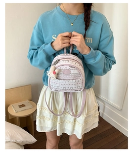 Detail of a floral patterned mini backpack with a plush pendant shown on a model