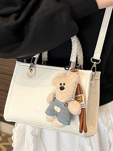 White square crossbody bag with woven handle and cute teddy bear charm accessory