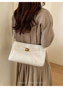 Close-up of beige vintage shoulder bag with retro metal buckle on a textured leather strap