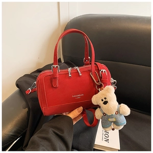 Dettaglio della borsa Boston in pelle rossa testurizzata con cerniere e ciondolo