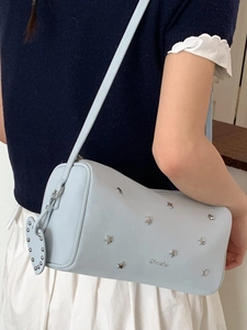 Light blue cylindrical shoulder bag with silver star rivets and a heart pendant detail