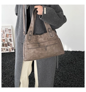Detail of vintage brown leather tote bag with parallel zippers and metal strap buckles