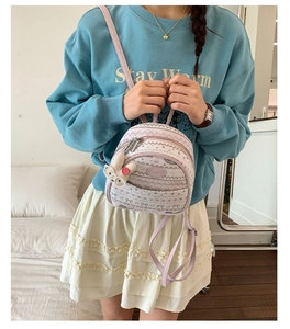 Detail of pink mini backpack with jacquard patterns and a cute rabbit doll charm