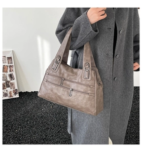 Close-up of taupe faux leather texture and double silver zipper details on handbag