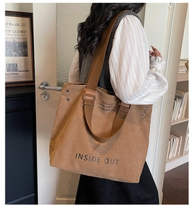 Close-up of brown canvas tote bag with INSIDE OUT text and reinforced metal rivets