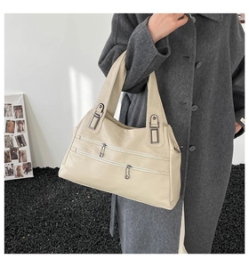 Detail view of beige PU leather tote bag with unique double horizontal zippers and silver hardware