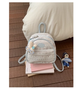 Close-up of Fair Isle jacquard patterns and cute rabbit plush charm on a beige backpack