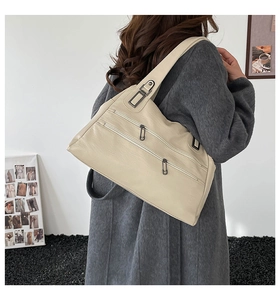 Close-up of beige leather shoulder bag with multiple zipper compartments and hardware