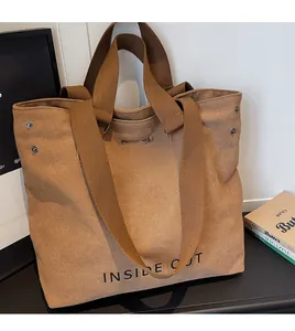 Detail view of khaki canvas tote bag with wide shoulder strap and metal rivets