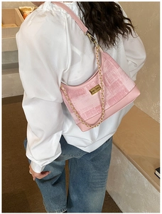 Detailed view of pink textured fabric bag with gold chain strap and metal lock closure