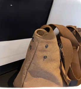Detailed close-up of brown canvas tote with silver metal snap buttons and thick woven strap