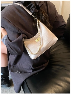 Detail of light beige canvas hobo bag with gold chain strap and metal buckle on model
