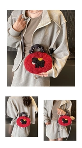 Detail of red plush crossbody bag with bull embroidery and black twisted top handle