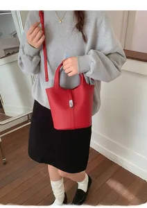 Detail van rode emmer-tas van lycheeleer met zilveren slot en afneembare schouderriem