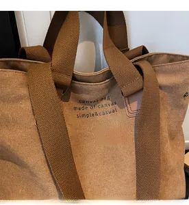 Detail showing thick brown canvas texture and durable woven shoulder strap of the tote bag