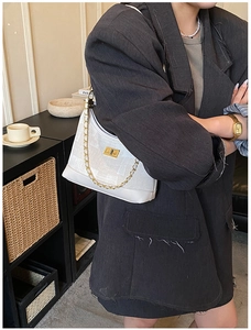White large capacity tote bag with gold chain strap and buckle shown on a model
