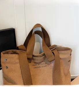 Detail of dark khaki canvas tote bag featuring reinforced handles and black typography